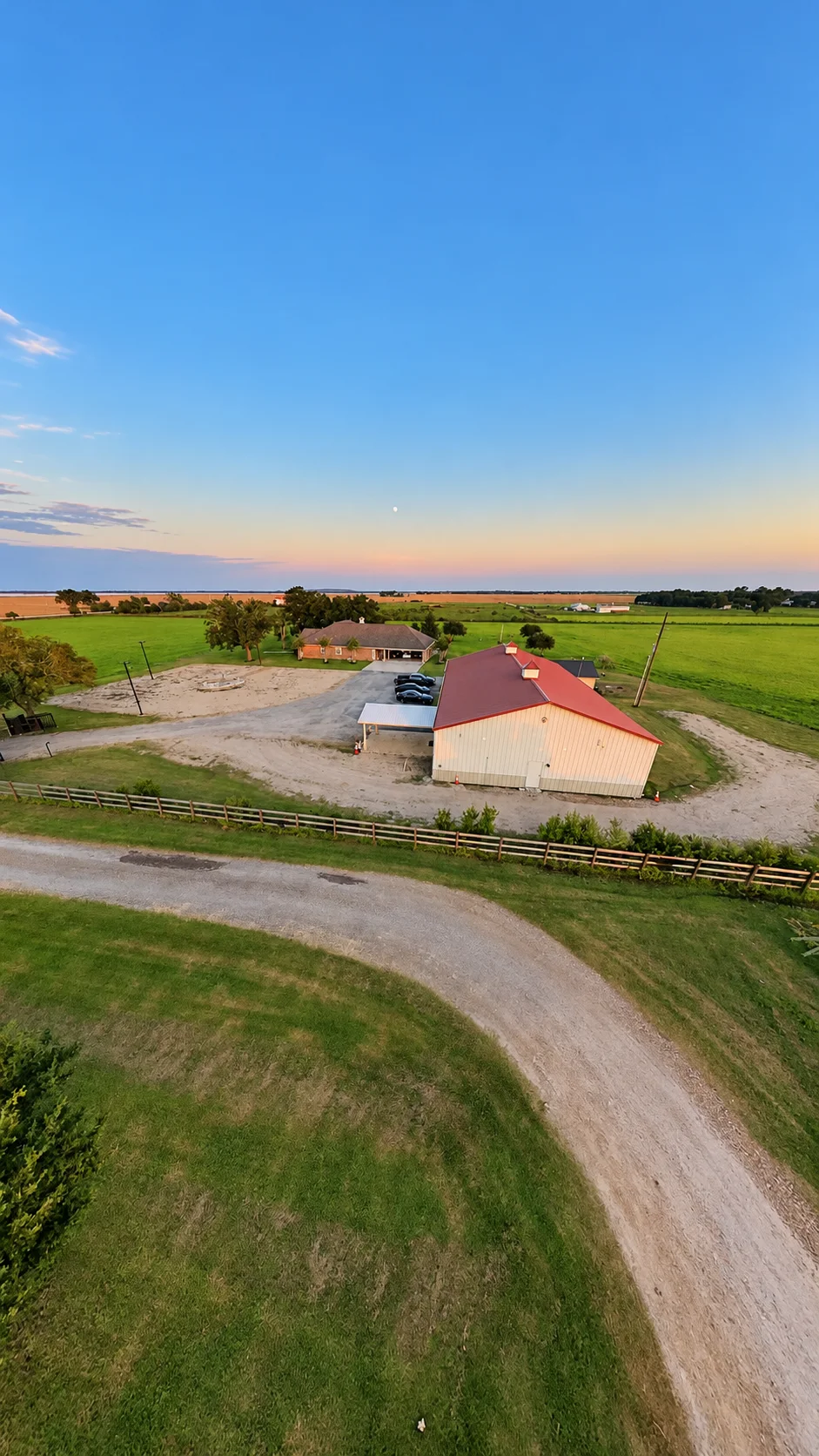 Aerial view of the curved ranch drive, fence, venue building, and surrounding fields
